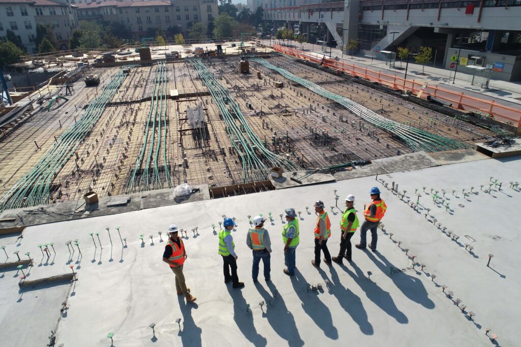 Seven men in hi-vis vests observing a construction site in BC