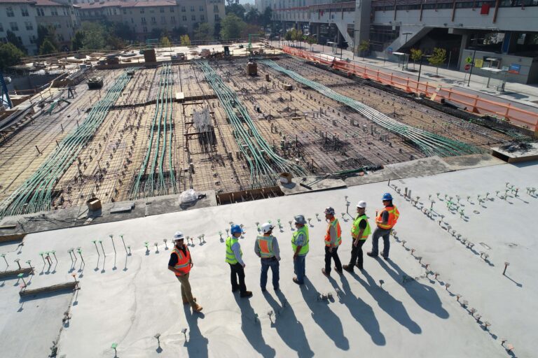 Seven men in hi-vis vests observing a construction site in BC