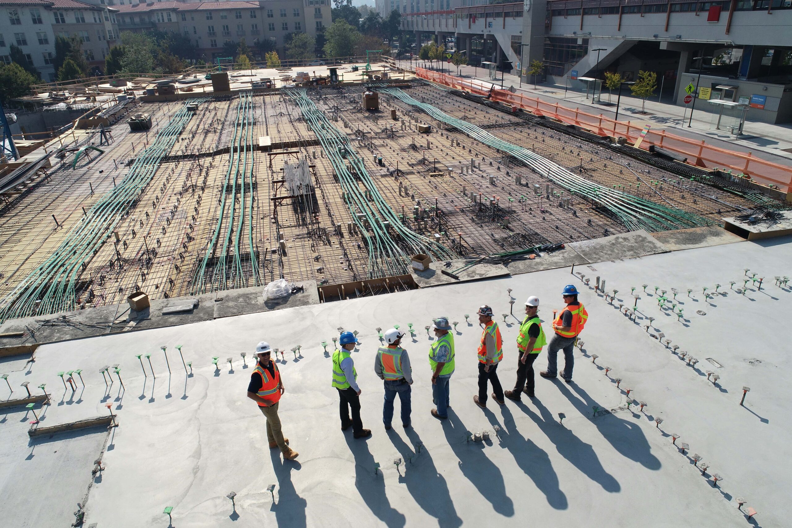 Seven men in hi-vis vests observing a construction site in BC