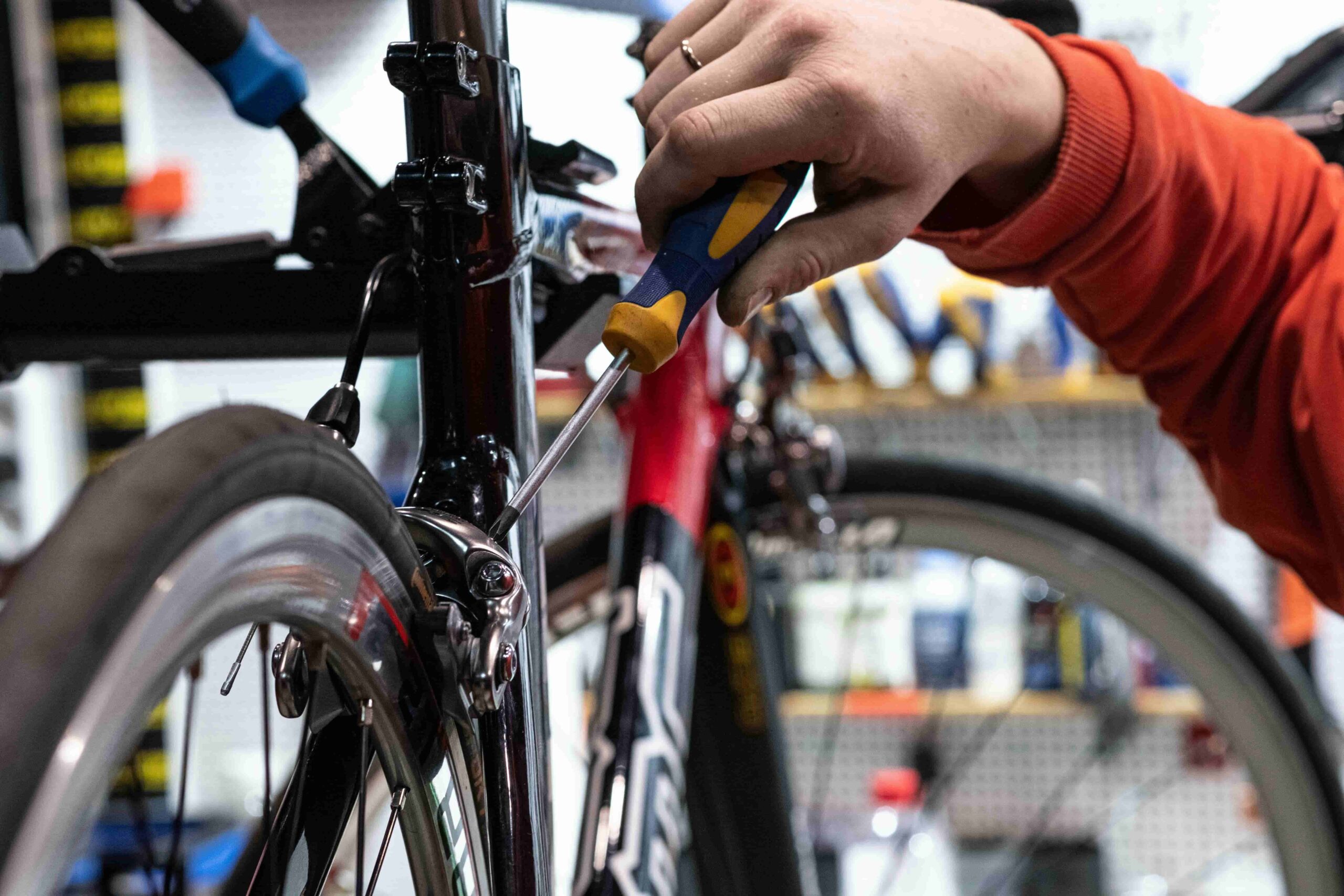 A man using a residential bike repair station to tighten a screw on his bike